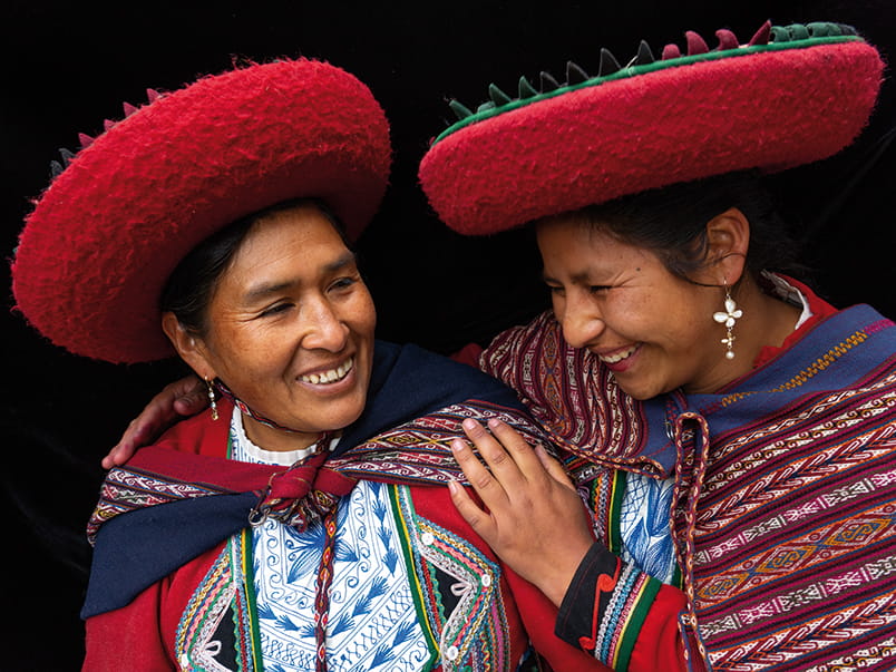 Portrait of two local women who are close friends, in colourful, predominantly red, traditional local dress and hats, Chinchero, Sacred Valley, Peru (Model Releases)